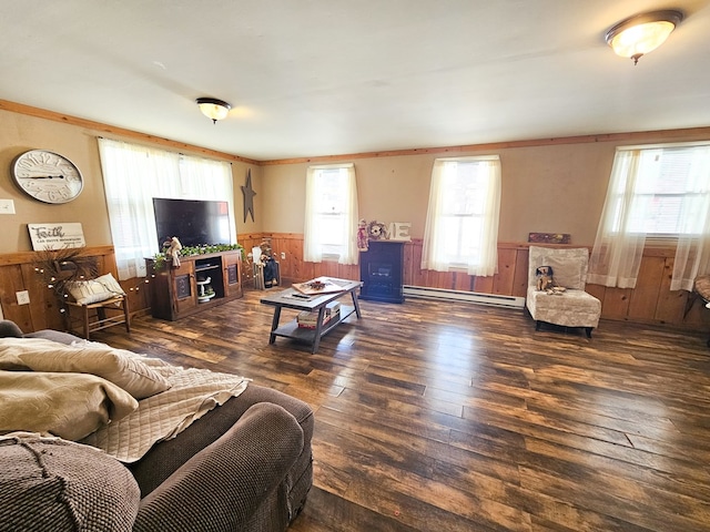 living area featuring dark wood-style flooring, wood walls, baseboard heating, and wainscoting