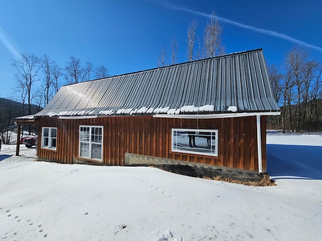 view of snowy exterior with metal roof and board and batten siding