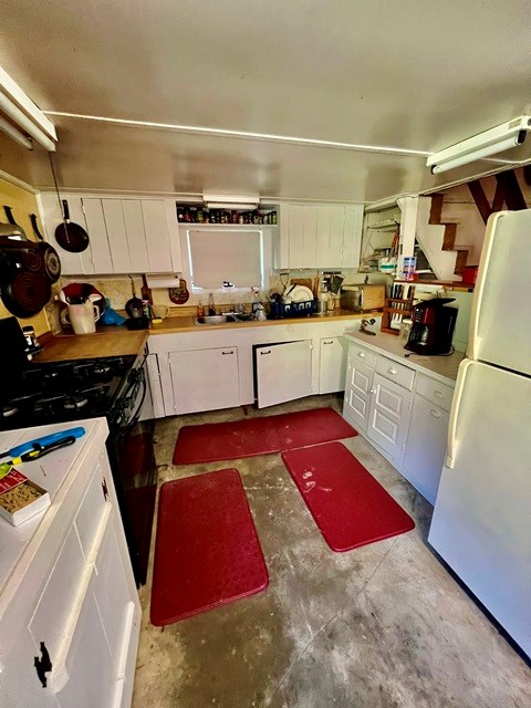 kitchen featuring white appliances, white cabinetry, sink, and concrete flooring