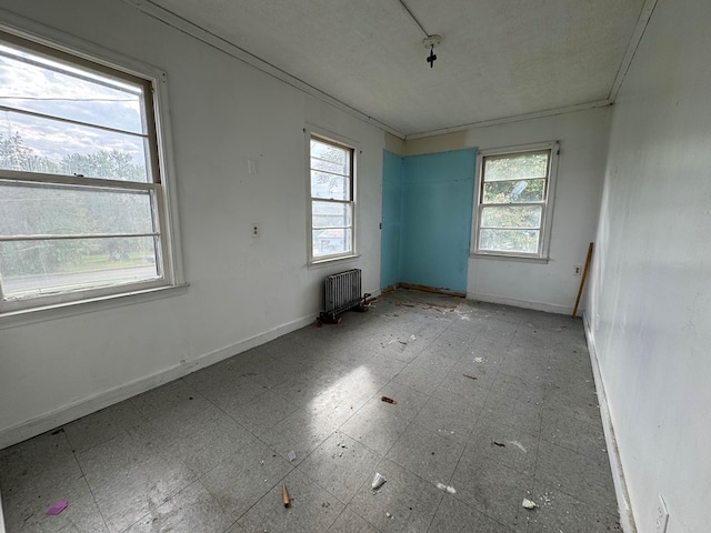 unfurnished room with radiator heating unit, crown molding, and a wealth of natural light