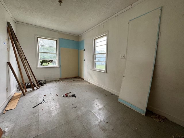 spare room featuring a textured ceiling and ornamental molding