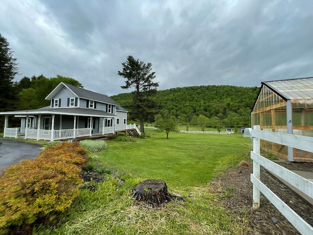 1571 State Route 44n, Coudersport, PA 16915 - view of yard featuring a greenhouse, a wooded view, covered porch, an outbuilding, and asphalt driveway