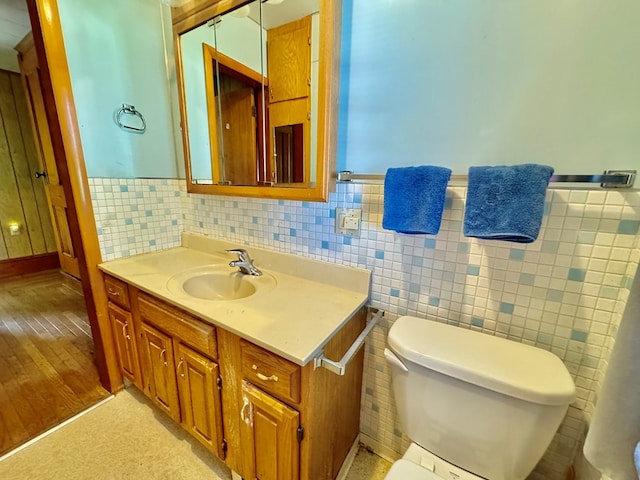 bathroom with vanity, tile walls, and toilet