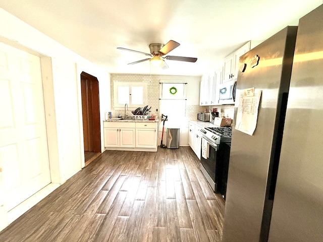 kitchen with white cabinets, sink, ceiling fan, appliances with stainless steel finishes, and tasteful backsplash