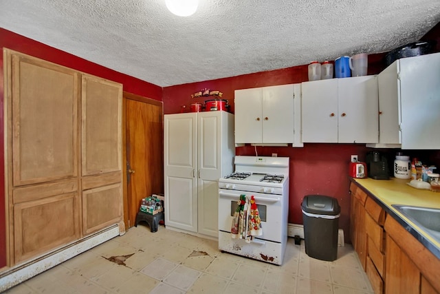 kitchen with a baseboard heating unit, a textured ceiling, white gas range oven, and sink