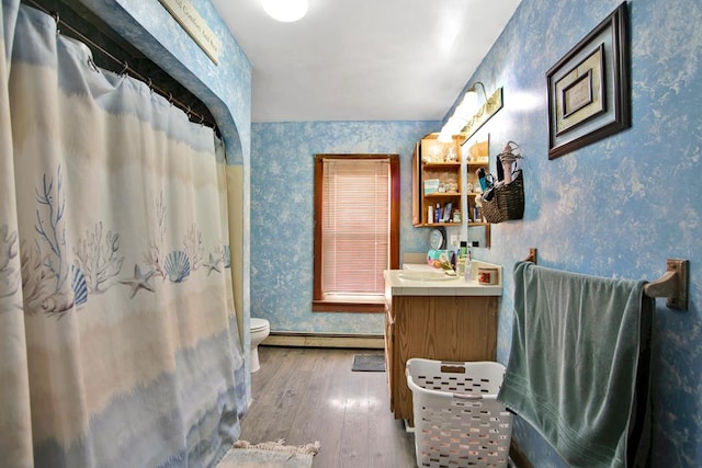 bathroom with a baseboard heating unit, toilet, wood-type flooring, and vanity