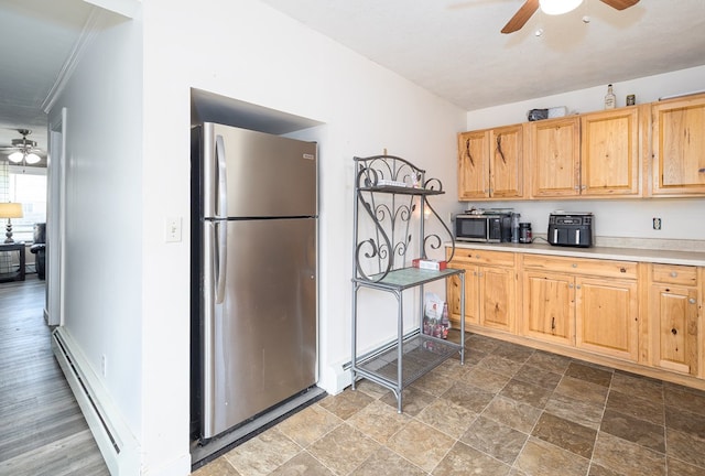 kitchen with light brown cabinets, a baseboard heating unit, stainless steel appliances, light countertops, and ceiling fan