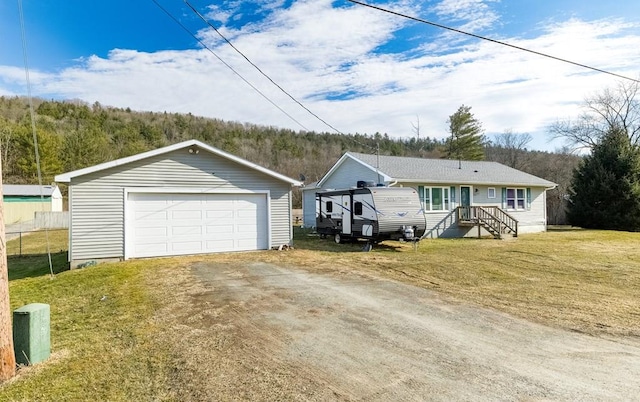 view of front of house featuring an outbuilding, a front yard, fence, a detached garage, and a view of trees