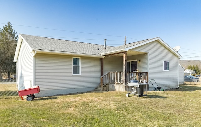 rear view of house featuring a yard, fence, and a shingled roof