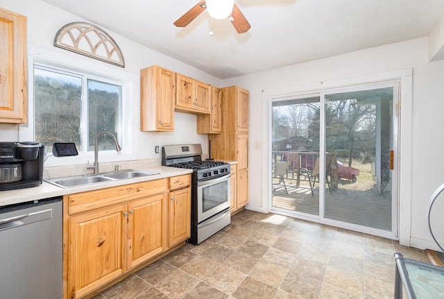 kitchen featuring a ceiling fan, a sink, light countertops, appliances with stainless steel finishes, and stone finish flooring
