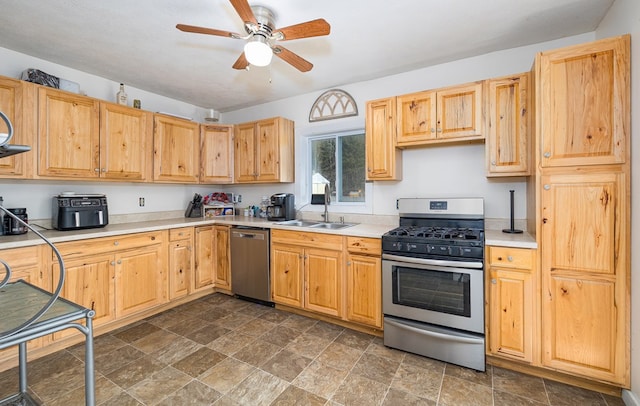 kitchen featuring stone finish flooring, ceiling fan, light countertops, appliances with stainless steel finishes, and a sink
