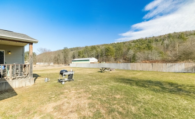 view of yard with a wooded view and fence