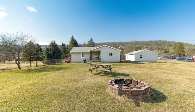 rear view of property with an outdoor fire pit, a yard, and fence