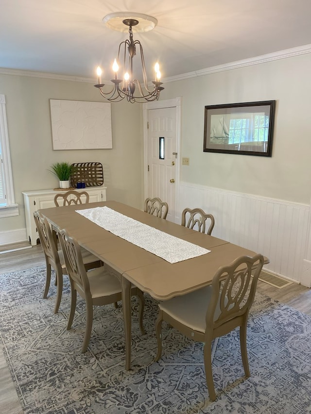 dining area featuring ornamental molding, hardwood / wood-style floors, and a notable chandelier