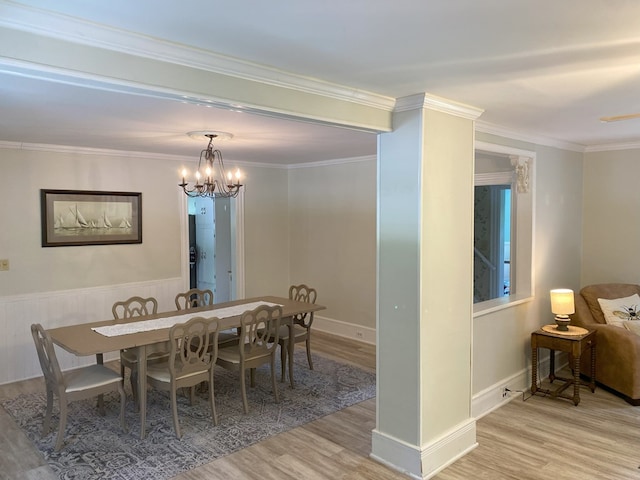 dining area with light hardwood / wood-style floors, crown molding, and an inviting chandelier