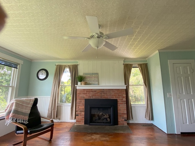 living room featuring ceiling fan, crown molding, a fireplace, and hardwood / wood-style flooring