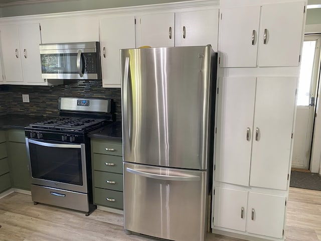 kitchen with white cabinets, appliances with stainless steel finishes, light hardwood / wood-style flooring, and tasteful backsplash