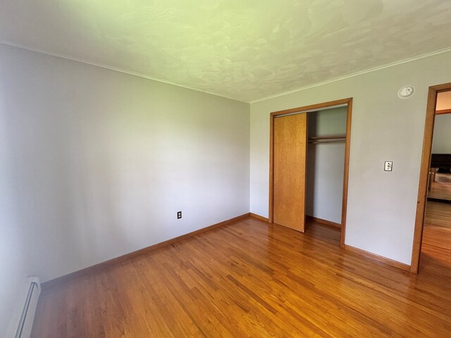 425 Gateway Industrial Park Rd, Athens, PA 18810 - unfurnished bedroom featuring wood finished floors, a closet, a textured ceiling, baseboards, and baseboard heating