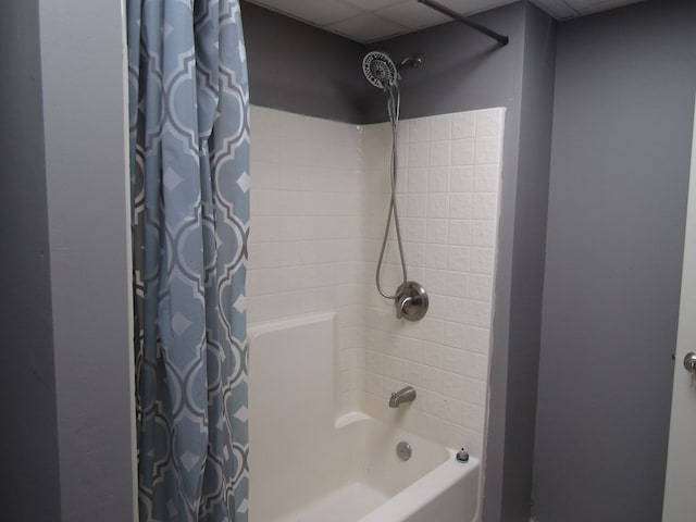 bathroom with a drop ceiling and shower / bath combo with shower curtain