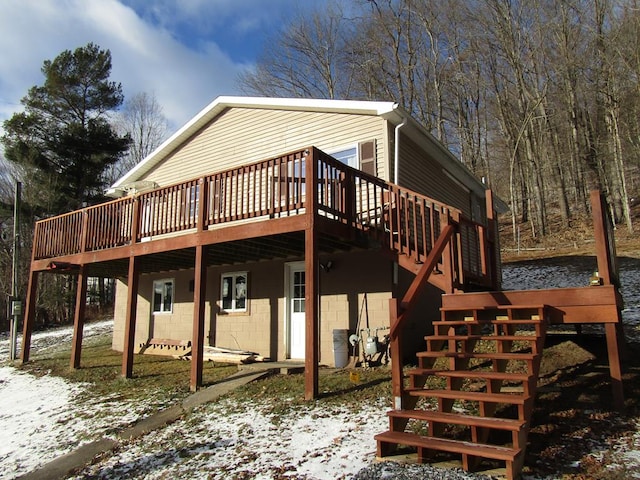 snow covered rear of property with a deck