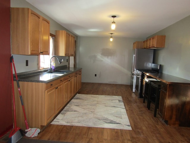 kitchen featuring gas range, dark hardwood / wood-style flooring, hanging light fixtures, and sink