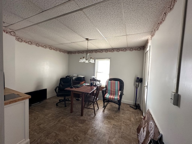 interior space with a paneled ceiling, baseboards, and an inviting chandelier