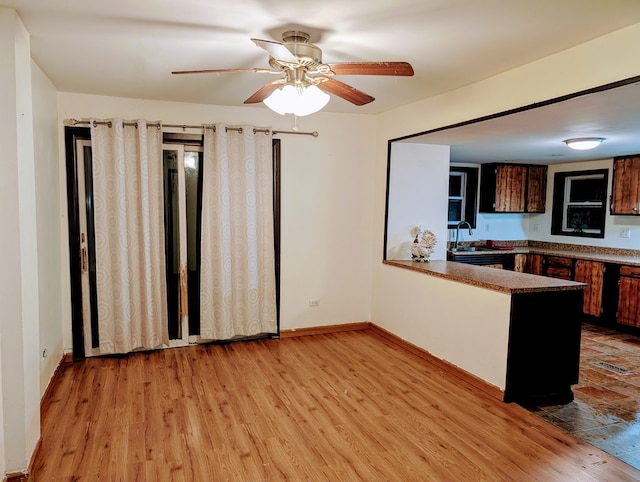 kitchen featuring sink, light hardwood / wood-style flooring, ceiling fan, dark brown cabinets, and kitchen peninsula