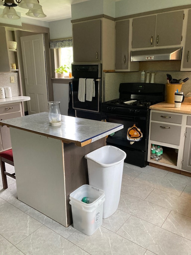 115 Pine St, Galeton, PA 16922 - kitchen featuring black appliances, under cabinet range hood, a breakfast bar area, a kitchen island, and light countertops