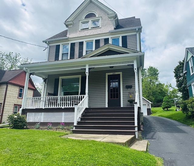 victorian home with covered porch, an outbuilding, and a front lawn
