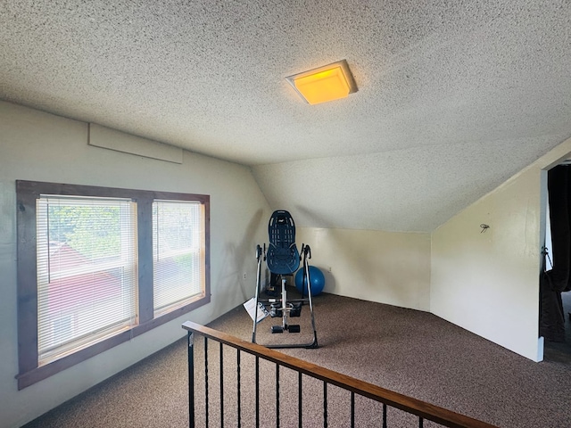 workout area with carpet, a textured ceiling, and vaulted ceiling