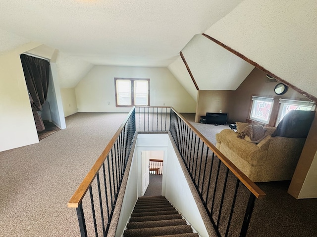stairs with carpet flooring, lofted ceiling, and a textured ceiling