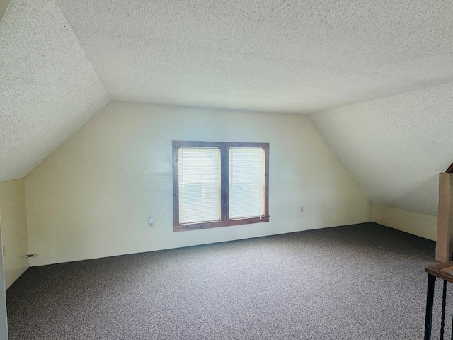 bonus room with vaulted ceiling, carpet floors, and a textured ceiling