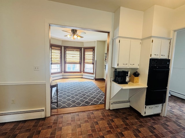 kitchen with oven, ceiling fan, white cabinets, baseboard heating, and a warming drawer