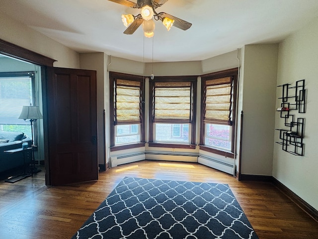 unfurnished room featuring wood finished floors, a ceiling fan, baseboards, and baseboard heating
