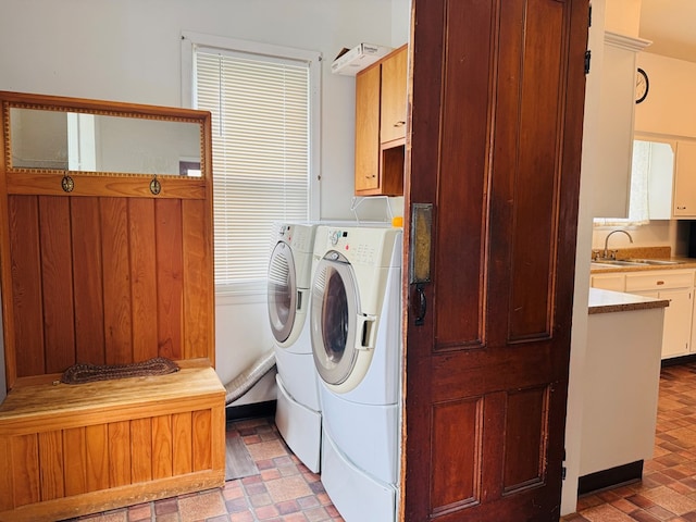washroom with cabinet space, washer and clothes dryer, and brick patterned floors