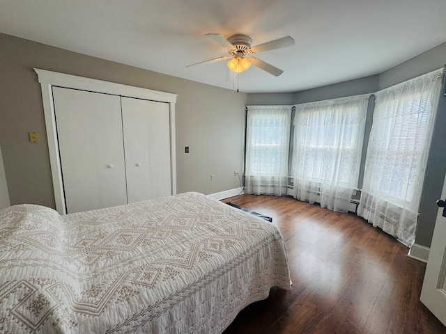 bedroom with wood finished floors, baseboards, a closet, and a ceiling fan
