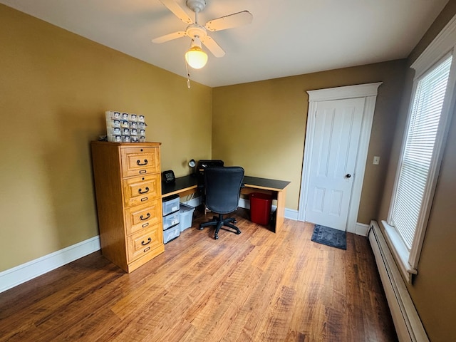 home office with baseboard heating, wood finished floors, ceiling fan, and baseboards