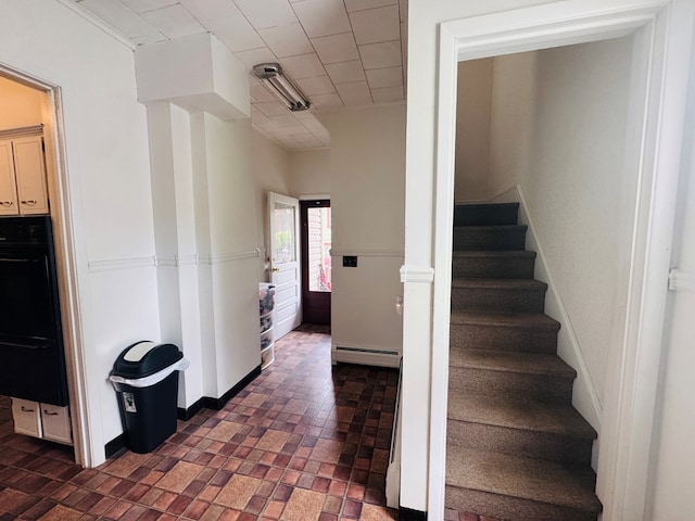 stairway featuring brick patterned flooring and a baseboard radiator