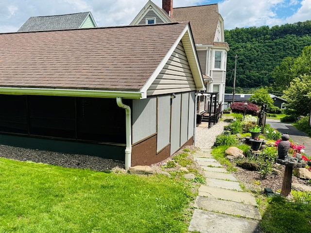 view of home's exterior featuring a chimney and roof with shingles