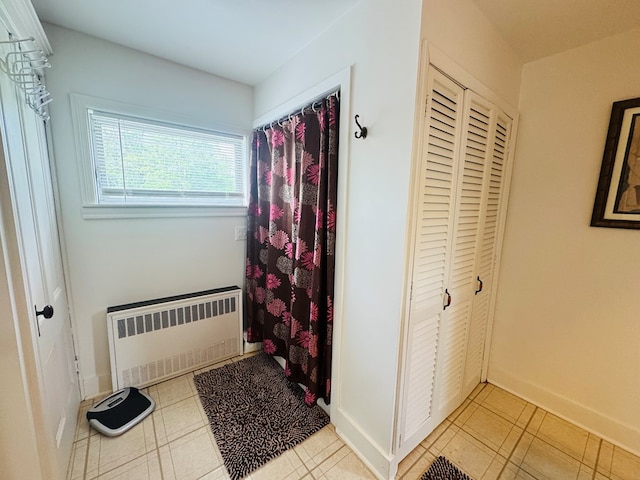 bathroom featuring radiator, tile patterned floors, baseboards, and a shower with shower curtain