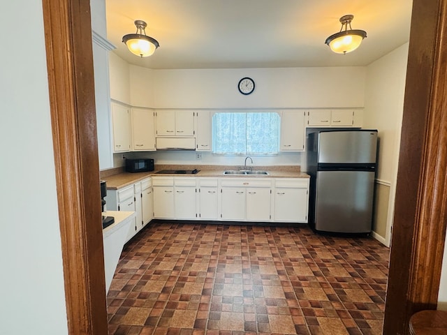 kitchen featuring black appliances, a sink, brick patterned flooring, light countertops, and white cabinetry