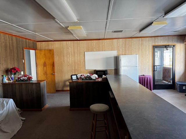 carpeted office featuring wood walls