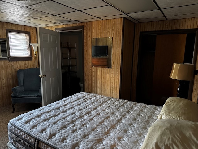 bedroom with carpet flooring, a drop ceiling, and wood walls