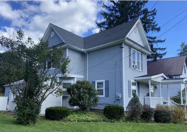 view of side of property with a lawn, cooling unit, and covered porch