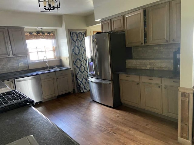 kitchen featuring appliances with stainless steel finishes, backsplash, sink, an inviting chandelier, and dark hardwood / wood-style floors