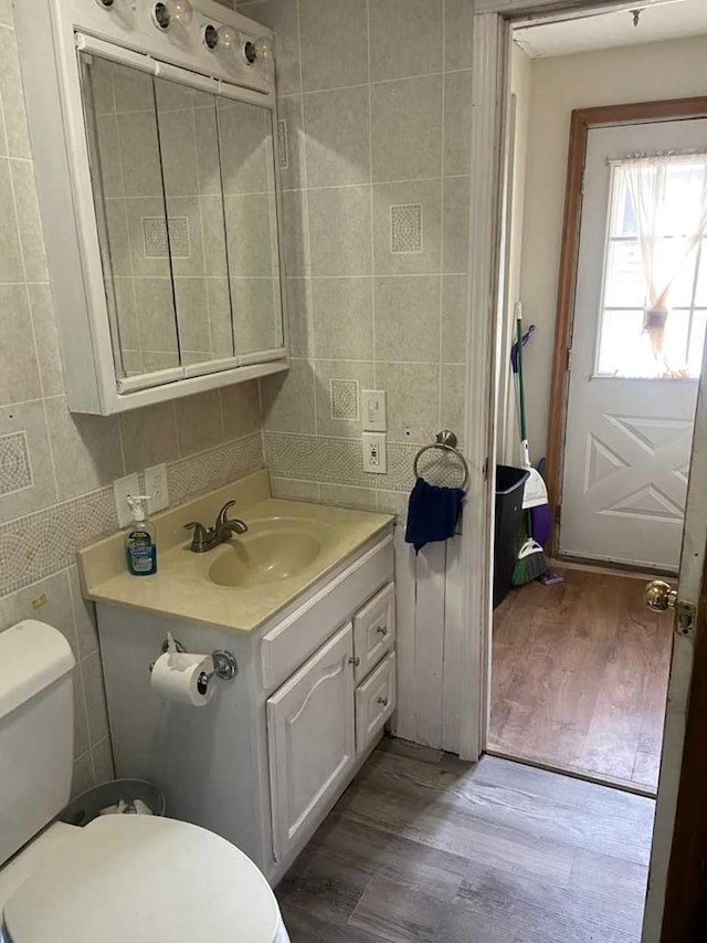 bathroom featuring hardwood / wood-style floors, vanity, toilet, and tile walls