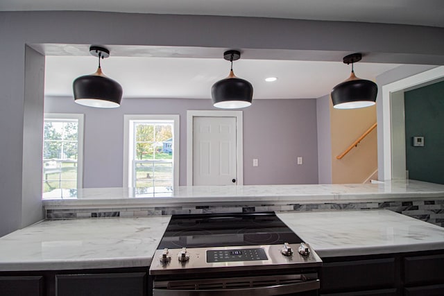 kitchen featuring light stone countertops, pendant lighting, and stainless steel electric range