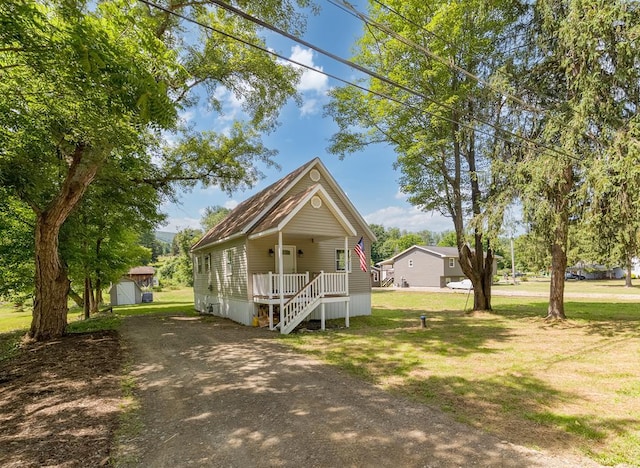 view of front of property with covered porch, a shed, and a front lawn