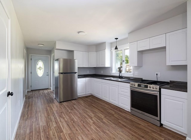 kitchen featuring dark wood-type flooring, white cabinets, sink, hanging light fixtures, and stainless steel appliances