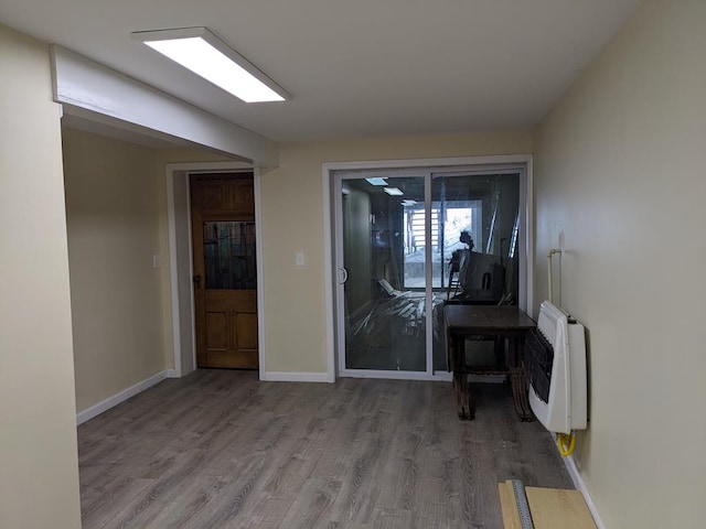 corridor with hardwood / wood-style floors and heating unit